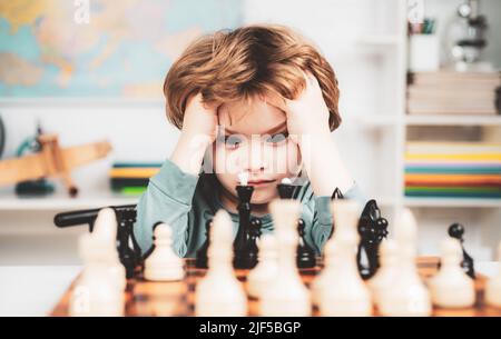 Garçon pense ou plan au jeu d'échecs, style vintage pour le concept d'éducation. École d'échecs. Garçon enfant jouant aux échecs à la maison. Banque D'Images