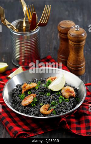 Paella noire avec crevettes et citron, fruits de mer espagnol sur table en bois Banque D'Images