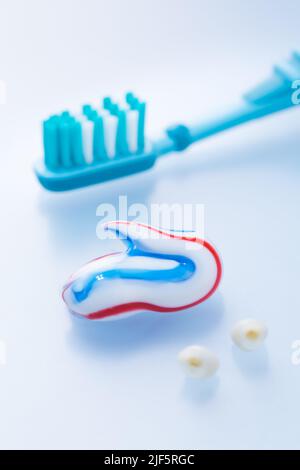 Dentifrice coloré et brosse à dents avec dents primaires sur fond bleu, concept de soins dentaires et d'hygiène Banque D'Images