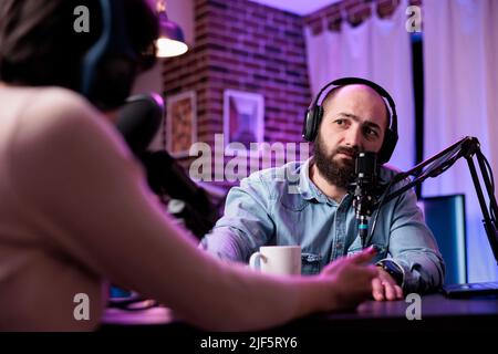 Un homme vlogger interviewer la personne sur la discussion de podcast, parlant à l'invité en studio. Jeune homme ayant une conversation avec un blogueur de médias sociaux, enregistrant des programmes pour le contenu de la chaîne. Banque D'Images