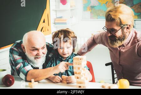 Les générations masculines amitié. Joyeux petit enfant père et grand-parent loisirs temps. Grangfather, Père et fils jouant au jeu à la maison. Banque D'Images