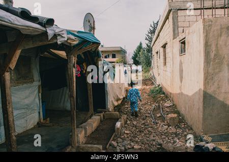 Garçon va à son ami, qui vit à l'extérieur du camp. Une matinée dans un camp de réfugiés dans la vallée de la Bekaa, environ 20 familles vivent. Certaines familles attendent depuis cinq ans d'aller à un autre endroit. Même si la situation leur permettrait de retourner en Syrie, la plupart d'entre eux sont simplement canít. Les enfants nés au Liban n'ont pas de passeport syrien mais sont enregistrés dans le pays. Par conséquent, les parents restent dans le pays aussi. Beaucoup de parents ont également leur permis de séjour expiré et ne peuvent pas se permettre d'en faire un nouveau, car beaucoup vivent avec deux à trois dollars par jour. Banque D'Images