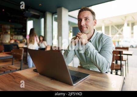 Jeune homme d'affaires assis dans un café travaillant avec un ordinateur portable Banque D'Images