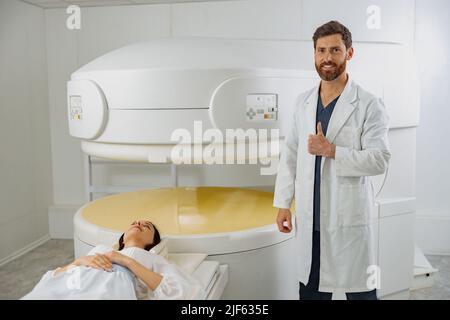 Radiologue sur l'arrière-plan de l'IRM, de l'acquisition CT ou PET avec le patient montrant le pouce vers le haut Banque D'Images