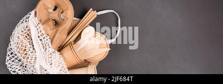 Set de vaisselle en papier écologique, ustensiles écologiques - tasses en papier, récipients, couverts en bambou en bois et pailles à boire dans un sac en coton net sur conc gris foncé Banque D'Images