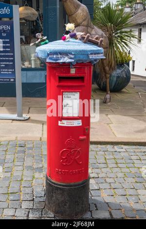 Couverture en tissu tricoté coloré sur une boîte aux lettres Royal Mail à Keswick, Cumbria Banque D'Images