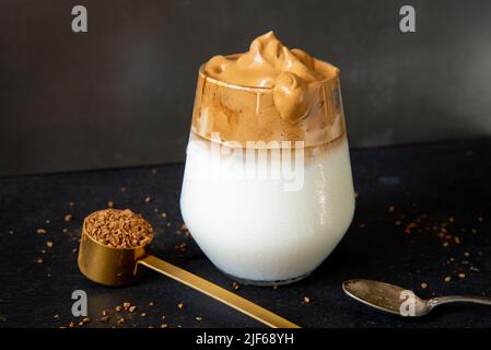 Café Dalgona. Boisson glacée au café de style coréen sur fond sombre. Café instantané fouetté avec du sucre et de l'eau pour un petit déjeuner savoureux. Très tendance co Banque D'Images