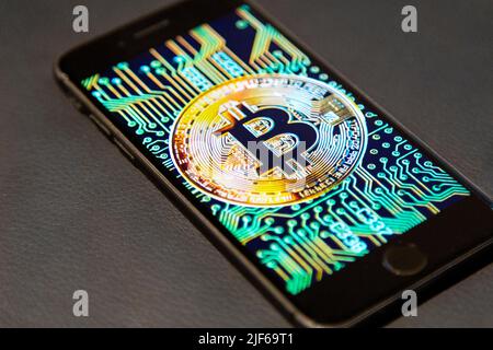 Logo Bitcoin sur un écran de téléphone contre un arrière-plan en cuir Banque D'Images