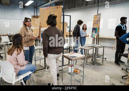 Professeur mature travaillant avec des étudiants en art pendant la classe de peinture à l'école - Focus sur le visage de femme Banque D'Images