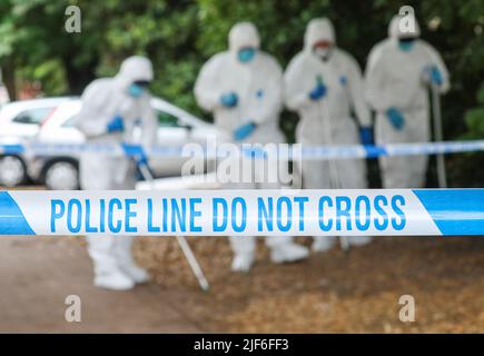 Des bandes de police sur une scène de crime au Royaume-Uni tandis que des scènes d'officiers de crime sont à la recherche. Banque D'Images