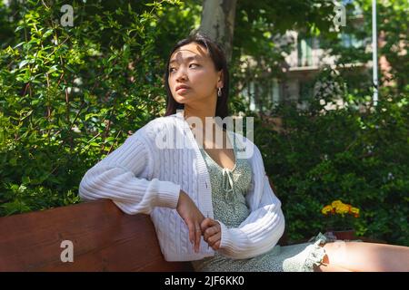 Contenu jardinier femelle dans un tablier debout avec des fleurs fraîches en pot assorties et des plantes à la table à la maison et regardant vers le bas Banque D'Images
