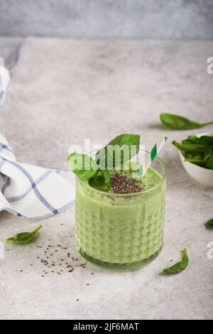 Smoothie aux épinards vert sain. Smoothie ou milkshake végétalien à partir d'épinards, de bananes et de graines de chia sur fond de table en béton gris. Manger propre, alkal Banque D'Images