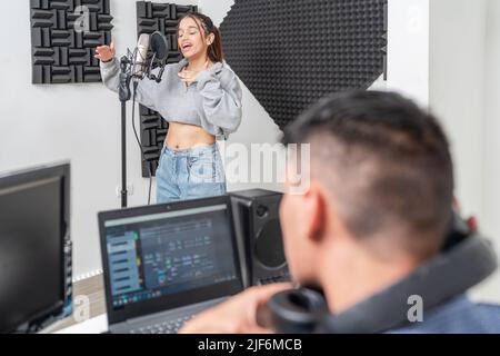 Jeune chanteuse enregistrant la voix dans le micro dans un studio de musique Banque D'Images