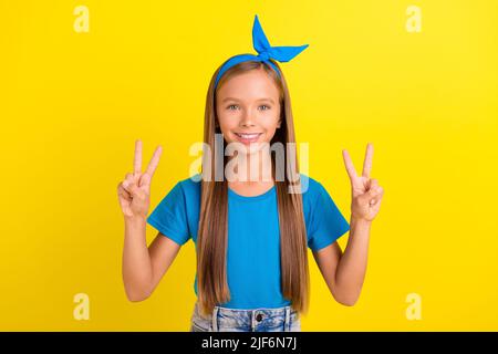 Portrait des mains positives adorables des filles les doigts démontrent le symbole de v-signe bonjour isolé sur fond jaune Banque D'Images