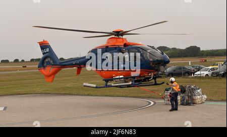 Cornwall, Angleterre, Royaume-Uni.2022. Un hélicoptère de transport aérien se soulève avec une cargaison dans une élingue et un signal de main du personnel de l'équipage au sol. Banque D'Images