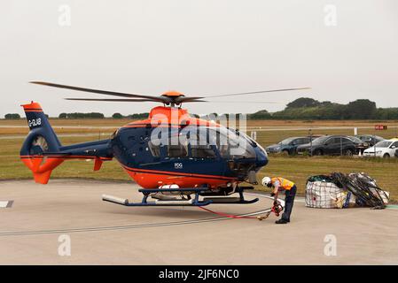 Cornwall, Angleterre, Royaume-Uni.2022. Un hélicoptère de transport aérien se soulève avec une cargaison dans une élingue et un signal de main du personnel de l'équipage au sol. Banque D'Images