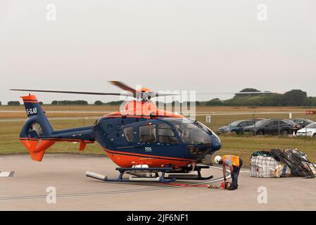 Cornwall, Angleterre, Royaume-Uni.2022. Un hélicoptère de transport aérien se soulève avec une cargaison dans une élingue. Signal du personnel au sol. Banque D'Images