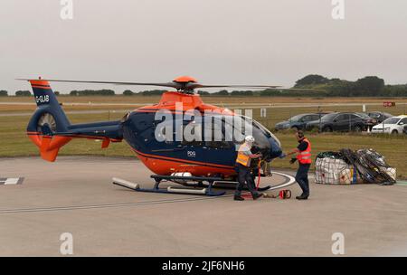 Cornwall, Angleterre, Royaume-Uni.2022. L'équipage au sol de l'hélicoptère de transport aérien fixant la sangle de transport au dessous du ventre de l'avion, puis à la cargaison dans un filet. Banque D'Images