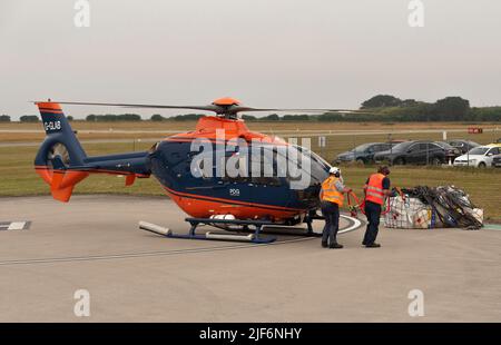 Cornwall, Angleterre, Royaume-Uni.2022. L'équipage au sol de l'hélicoptère de transport aérien fixant la sangle de transport au dessous du ventre de l'avion, puis à la cargaison dans un filet. Banque D'Images