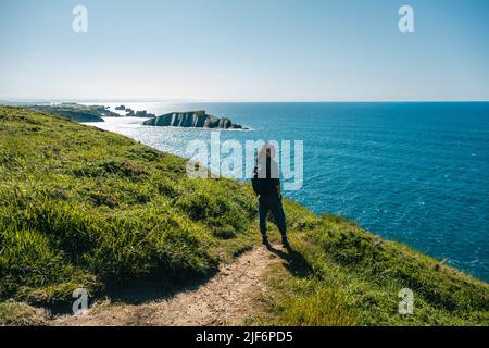 Pleine longueur de femme aventureuse avec sac à dos debout sur la falaise tout en voyageant en Cantabrie Banque D'Images