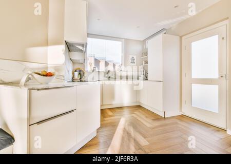 Fragment de l'intérieur de la lumière étroite cuisine maison avec style minimaliste mobilier blanc avec évier et cuisinière Banque D'Images