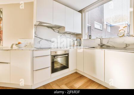 Fragment de l'intérieur de la lumière étroite cuisine maison avec style minimaliste mobilier blanc avec évier et cuisinière Banque D'Images