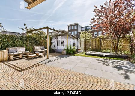 Beau patio pavé avec coin salon et petit jardin près de la clôture en bois Banque D'Images