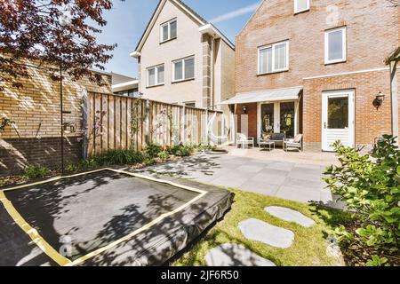 Beau patio pavé avec coin salon et petit jardin près de la clôture en bois Banque D'Images