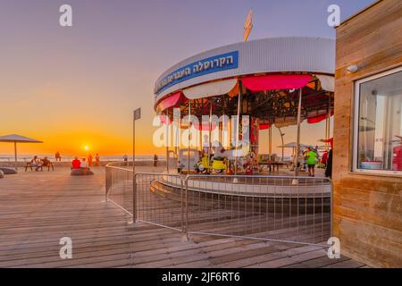 Tel-Aviv, Israël - 28 juin 2022 : coucher de soleil sur le complexe portuaire, avec le carrousel historique et les visiteurs, à tel-Aviv, Israël Banque D'Images