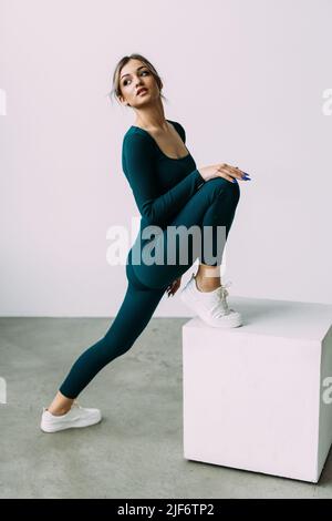 bien-construit sweaty fille faisant sauter la boîte au centre de sport. pleine longueur vue latérale photo. temps libre activité. Banque D'Images