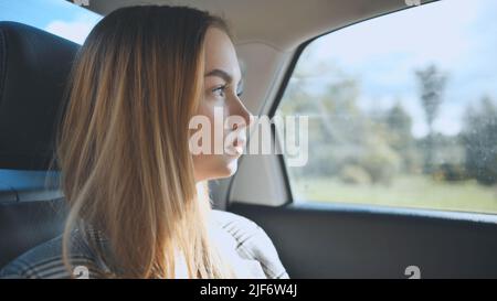 Une jeune fille roule dans une voiture à l'arrière. Banque D'Images