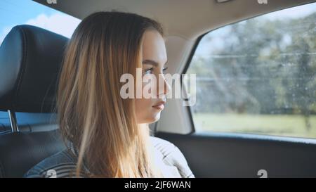 Une jeune fille roule dans une voiture à l'arrière. Banque D'Images