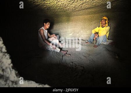 Les travailleurs sont photographiés pendant qu'ils se reposent de creuser et de sculpter dans la roche pour construire une chambre pour la tombe traditionnelle de chambre de pierre dans le nord de Toraja, le sud de Sulawesi, en Indonésie. Banque D'Images