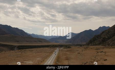 Montagne vallée de l'Altaï avec des voitures de circulation sur l'autoroute Chuya sous le ciel spectaculaire, Sibérie, Russie. Magnifique paysage de nature d'été pendant la journée. Banque D'Images