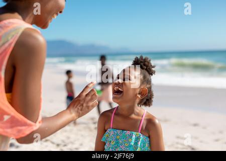 Mère et fille afro-américaine joyeuse appréciant une journée ensoleillée à la plage avec la famille, espace copie Banque D'Images