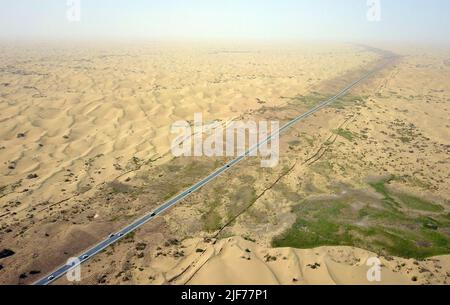 (220630) -- YULI, 30 juin 2022 (Xinhua) -- une photo aérienne montre des voitures qui circulent sur une nouvelle autoroute traversant le désert de Taklimakan dans la région autonome de Xinjiang, au 30 juin 2022, dans le nord-ouest de la Chine. Située dans la préfecture autonome mongole de Bayingolin, au sud du Xinjiang, l'autoroute reliant le comté de Yuli et le comté de Qiemo a été mise en service jeudi. L'autoroute est la troisième à travers le désert de Taklimakan, le deuxième plus grand désert de sable mobile au monde. Avec une vitesse prévue de 60 ou 80 km/h pour différentes sections, la route a une longueur totale de 334 km, avec 307 km de passage Banque D'Images