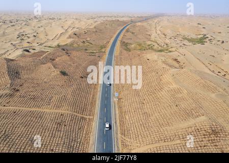 (220630) -- YULI, 30 juin 2022 (Xinhua) -- une photo aérienne montre des voitures qui circulent sur une nouvelle autoroute traversant le désert de Taklimakan dans la région autonome de Xinjiang, au 30 juin 2022, dans le nord-ouest de la Chine. Située dans la préfecture autonome mongole de Bayingolin, au sud du Xinjiang, l'autoroute reliant le comté de Yuli et le comté de Qiemo a été mise en service jeudi. L'autoroute est la troisième à travers le désert de Taklimakan, le deuxième plus grand désert de sable mobile au monde. Avec une vitesse prévue de 60 ou 80 km/h pour différentes sections, la route a une longueur totale de 334 km, avec 307 km de passage Banque D'Images