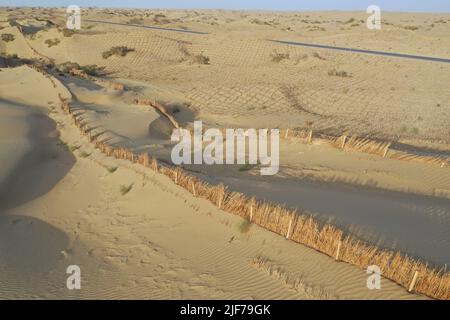 (220630) -- YULI, 30 juin 2022 (Xinhua) -- une photo aérienne montre des barrières de sable le long d'une nouvelle autoroute traversant le désert de Taklimakan dans la région autonome de Xinjiang, au 27 juin 2022, dans le nord-ouest de la Chine. Située dans la préfecture autonome mongole de Bayingolin, au sud du Xinjiang, l'autoroute reliant le comté de Yuli et le comté de Qiemo a été mise en service jeudi. L'autoroute est la troisième à travers le désert de Taklimakan, le deuxième plus grand désert de sable mobile au monde. Avec une vitesse prévue de 60 ou 80 km/h pour différentes sections, la route a une longueur totale de 334 km, avec 307 km de passage Banque D'Images