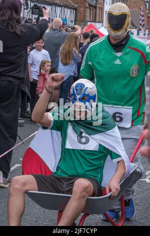 Un homme lève le bras alors qu’il est poussé dans une brouette par un autre homme pendant la course de la brouette à la fête de la Saint-Georges. Pinner, Harrow, Nort Banque D'Images