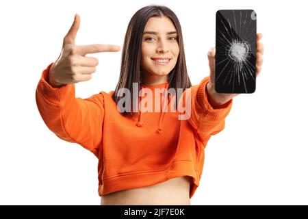 Jeune femme pointant vers un smartphone avec un écran cassé isolé sur fond blanc Banque D'Images