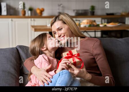 Mignon enfant jeune fille présentant boîte cadeau salutation bonne maman à la maison. Banque D'Images