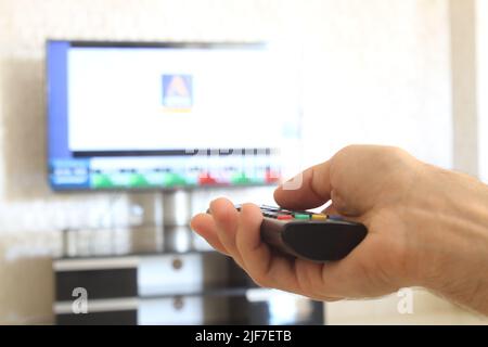 Télécommande, un homme avec une télécommande dans sa main change de chaîne sur le téléviseur. Banque D'Images