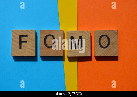 FOMO isolé lettres de l'alphabet en bois sur fond, abréviation de peur de manquer dehors Banque D'Images