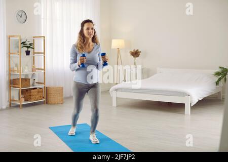 La femme enceinte effectue des exercices de sport à la maison pour maintenir une bonne forme du corps au troisième trimestre. Banque D'Images