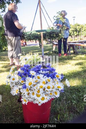 Au milieu de l'été en Suède, parents et enfants nouent des fleurs sur une grande couronne à malmkoping, en Suède Banque D'Images