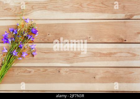 La cloche violette fleurit sur un fond de bois lors d'une journée ensoleillée d'été pour Félicitations. Espace pour la copie. Banque D'Images