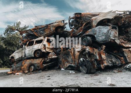 BUCHA, UKRAINE 22.06.2022 Irpin, Bucha. Cimetière de voitures. Voitures détruites à la suite de la guerre. Une montagne de voitures brûlée. Banque D'Images