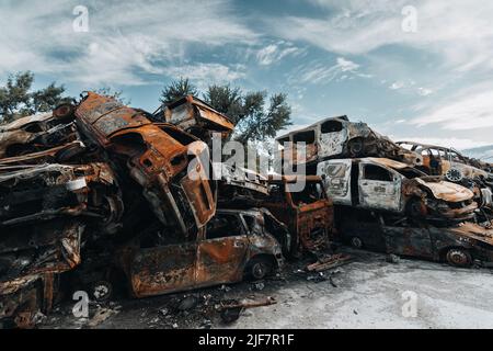 BUCHA, UKRAINE 22.06.2022 Irpin, Bucha. Cimetière de voitures. Voitures détruites à la suite de la guerre. Une montagne de voitures brûlée. Banque D'Images