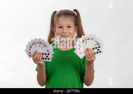 Portrait en gros plan d'une fille caucasienne avec des cartes à jouer. Isolé sur fond blanc. Concept de l'enfance. Temps libre, amusement, passe-temps, fille magicienne. Banque D'Images