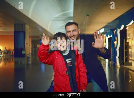 Beau père de l'homme du Moyen-Orient et son adorable fils, passagers, agitant regardant la caméra tout en marchant dans les magasins hors taxes de l'a international Banque D'Images